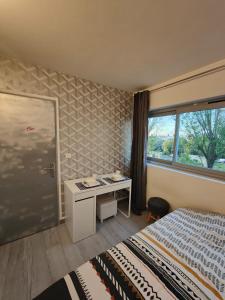 1 dormitorio con cama, escritorio y ventana en Appartement La parisienne, en Fresnes
