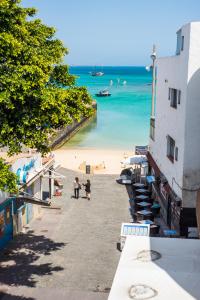 two people walking on a beach next to the ocean at 4rooms Fuerteventura in Corralejo