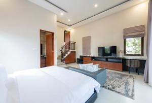 Schlafzimmer mit einem weißen Bett und einem TV in der Unterkunft THE LUXOR 5 Bedrooms Villa Vimala Hills in Gadok 1