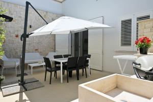 un ombrellone bianco su un patio con tavolo e sedie di Altamarea Beach Experience Villetta SE a Marina di Pescoluse