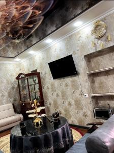 uma sala de estar com uma mesa e uma televisão na parede em «Gulnara» Luxurious house for rent as a whole new 5 rooms and a yard. em Samarkand
