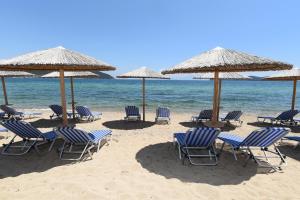a group of chairs and umbrellas on a beach at Edem Luxury Apartments in Nea Peramos