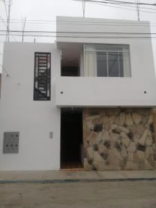 a white building with a window and a stone wall at Apartamentos Cristo Rey. in Tacna