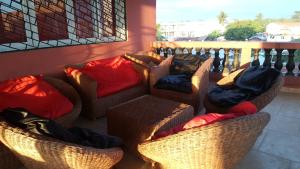 three wicker chairs with blankets and pillows on a balcony at Villa Cali SONOMA in Sambava