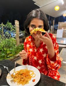 a woman sitting at a table with a plate of spaghetti at DE LUMA Beach View in Puducherry