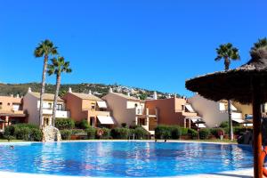 una gran piscina con palmeras y edificios en Playa Blanca Zahara en Zahara de los Atunes