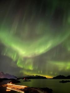 una aurora en el cielo sobre un cuerpo de agua en Lofoten view, en Kabelvåg