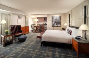 ケンブリッジにあるザ チャールズ ホテル イン ハーバード スクエアのベッドとリビングルームが備わるホテルルームです。