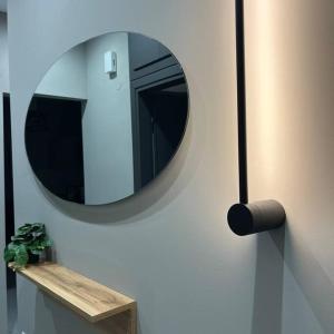 a round mirror on a wall with a wooden shelf at KM Ethnikis Amynis A in Drama