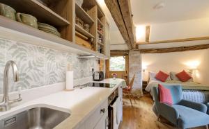 una cocina con fregadero y una cama en una habitación en Hayloft studio in historic barn, en Saint Briavels