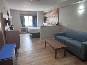 Habitación de hotel con sofá y cama en Days Inn & Suites by Wyndham Greeley en Greeley