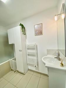 a white bathroom with a sink and a refrigerator at Le Cocon des Thermes Amneville Metz Luxembourg in Amnéville