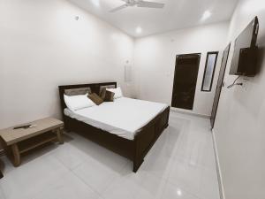 een kleine slaapkamer met een bed en een tafel bij Saryu Lodge near Ram Janam Bhumi in Ayodhya