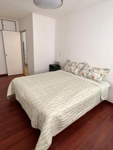 ein Schlafzimmer mit einem großen Bett und einer gestreiften Decke in der Unterkunft Refugio Urbano in Neuquén