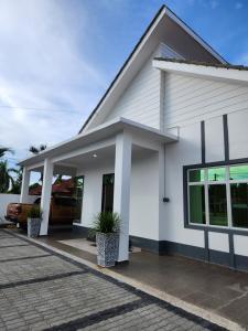a white house with a car parked in the driveway at Nusa Villa Garden in Kota Bharu