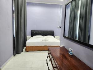 a bedroom with a bed and a table and a mirror at Nusa Villa Garden in Kota Bharu