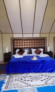 a bedroom with a bed with a blue blanket and pillows at Luxury Sahara Camp in Merzouga