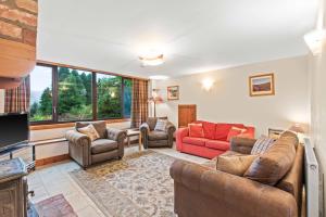 uma sala de estar com sofás e uma televisão em Freuchies Mill - A Holiday Home For All Seasons. em Blairgowrie