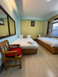 Habitación con 2 camas, silla y espejo. en Golden Gate Guest House, en Bhaktapur