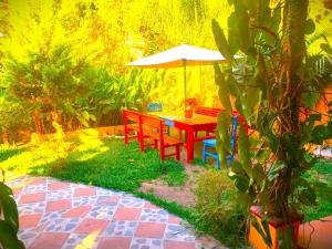 a red table and chairs with an umbrella in a garden at Art & Coffee in Santa Cruz La Laguna