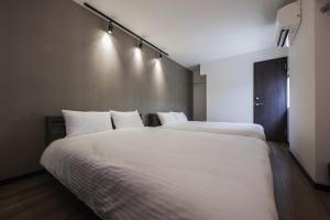 two beds in a room with white sheets and lights at Shiki Homes | RURI - Vacation STAY 12774 in Osaka