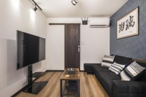 a living room with a black couch and a flat screen tv at Shiki Homes | RURI - Vacation STAY 12774 in Osaka