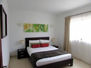 a bedroom with a large bed with red pillows at Peaceful Paradise at Tortuga Beach - 473 in Prainha