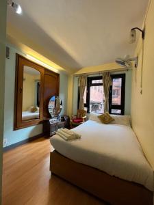 1 dormitorio con 1 cama grande y espejo grande en Golden Gate Guest House, en Bhaktapur