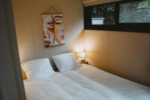 een slaapkamer met een bed met 2 witte kussens bij Boshuisje Rekem - Alma in Lanaken