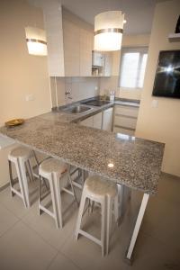 a kitchen with a granite counter top and stools at COMODO DEPARTAMENTO CERCA DE LA PLAYA WIFFI in Tonsupa