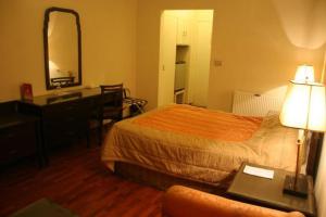 a hotel room with a bed and a desk and a mirror at Carlton Tower Hotel Lahore in Lahore