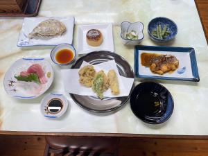 una mesa cubierta con platos de comida y salsa de inmersión en Ryokan Warajisha - Vacation STAY 80171v, en Goto
