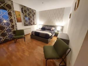 a bedroom with a bed and two chairs at Villa Tiviti in Oviedo