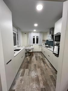 una cucina con armadietti bianchi e pavimenti in legno di La Chabola a Sobarzo