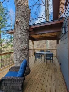 una terraza con un árbol, una mesa y sillas en The Aerie Luxury Near Asheville, en Marshall
