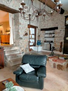 una silla de cuero en una sala de estar con una pared de piedra en Chez Nath et Oli, en Caunes-Minervois