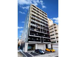 dwa samochody zaparkowane przed wysokim budynkiem w obiekcie VILLA KOSHIDO KOTONI - Vacation STAY 49578v w mieście Sapporo