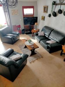 a living room with black leather couches and a table at Chez Nath et Oli in Caunes-Minervois