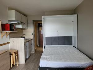 1 dormitorio con 1 cama con cabecero blanco grande en Studio refait à neuf avec balcon Ouest Résidence Le Galaxie, en Villard-de-Lans