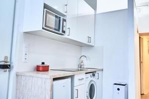 a kitchen with white cabinets and a microwave at Appartement moderne et lumineux - Centre ville Creil in Creil +6 photos