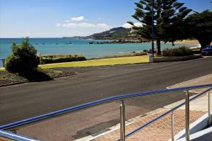 an empty road next to a beach with the ocean at Penguin Beachfront Apartments in Penguin