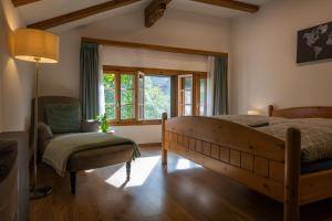 um quarto com uma cama, uma cadeira e uma janela em Chalet Elza em Lauterbrunnen