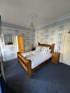 ein Schlafzimmer mit einem Bett mit blauen und weißen Tapeten in der Unterkunft Caer Menai in Caernarfon