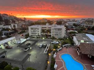 una puesta de sol sobre una ciudad con un aparcamiento con piscina en Reñaca Departamento Holiday Park 605 cómodo y buena ubicación familiar, en Viña del Mar