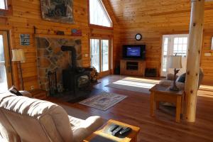 a living room with a fireplace in a log cabin at Mountain Maryland! Bear in the Woods in Grantsville