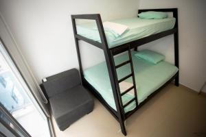 two bunk beds in a room with a chair at Hermoso departamento frente al mar, Arena Plaza in Tonsupa