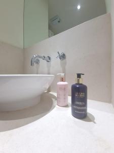 a bathroom with two bottles of soap and a sink at Lux 2 Bed Flat in Canary Wharf in London