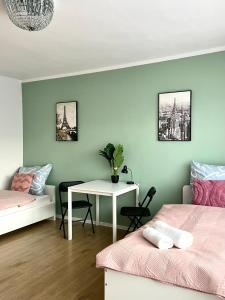 Cette chambre comprend deux lits, une table et un bureau. dans l'établissement Beautiful rooms in Szczecin - parking Gratis, à Szczecin