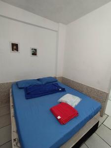 ein Schlafzimmer mit einem blauen Bett und einem roten Handtuch darauf in der Unterkunft Seu Apto na Praia da Costa 2 Local Excelente Ar Cond Frigobar Microondas Tv Todo seu Centro in Vila Velha