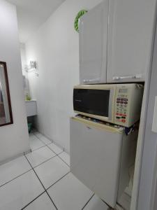 eine Mikrowelle auf einem Kühlschrank in der Küche in der Unterkunft Seu Apto na Praia da Costa 2 Local Excelente Ar Cond Frigobar Microondas Tv Todo seu Centro in Vila Velha